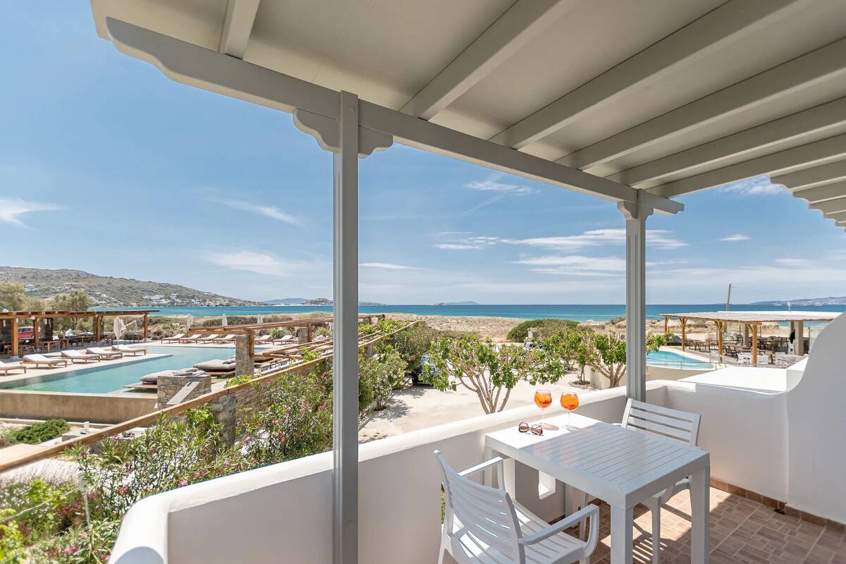 A terrace with a pool, outdoor seating, and a view of the sea.