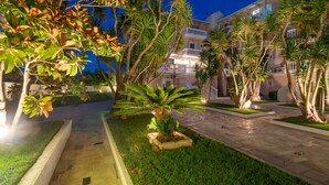 A well-maintained outdoor area with a paved walkway, palm trees, and a building with balconies. - Hotel Zakynthos  (Zakynthos)