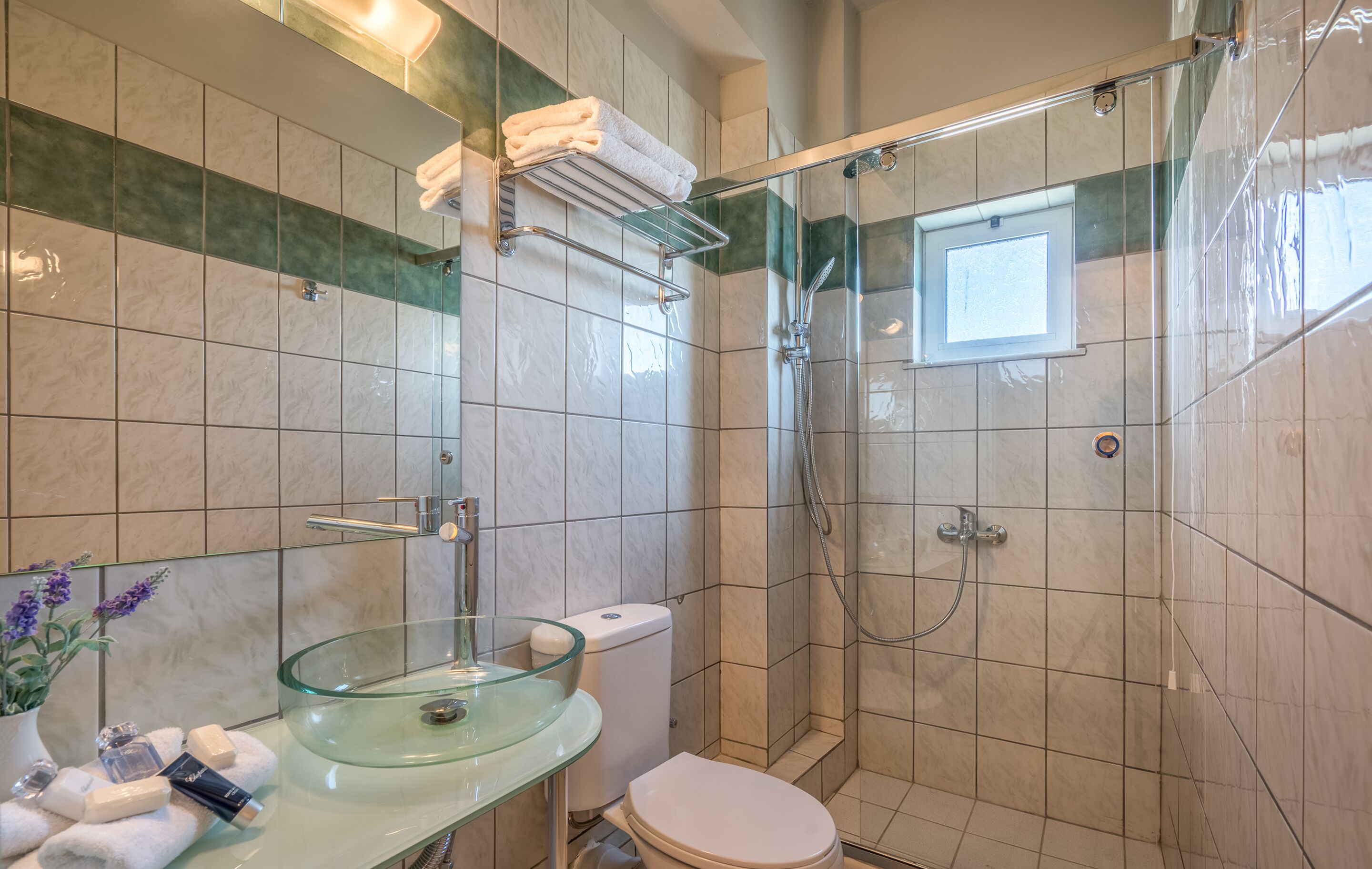 Un bagno con lavabo in vetro, water bianco e doccia con porta in vetro.