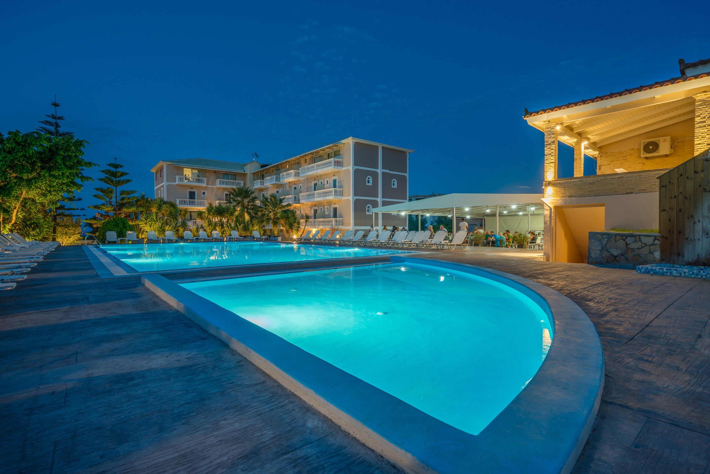 A swimming pool area with lounge chairs and a building in the background.