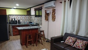 A compact living space with a kitchen, a dining area, and a seating area. - San Gabriel Apartments (La Fortuna)