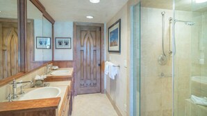 A bathroom with two sinks, a shower, and a door with a mirror. - Penthouse At The Peaks 744 (Mountain Village)