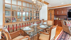 Un coin repas avec une table en verre, des chaises en bois et un banc agrémenté d’un coussin coloré.