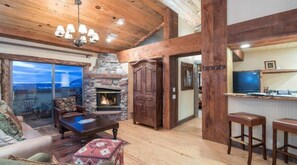 A spacious living area with a stone fireplace, wooden beams, and a bar area. - Penthouse At The Peaks 614 (Mountain Village)
