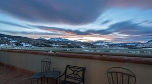A terrace with chairs and a view of a snowy landscape.