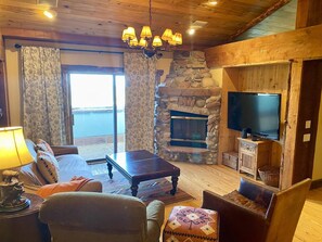 A cozy living room with a stone fireplace, a television, and a comfortable seating area. - Penthouse At The Peaks 614 (Mountain Village)