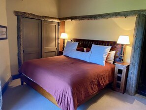 A bed with a wooden headboard, two bedside lamps, and a door with a rustic frame.