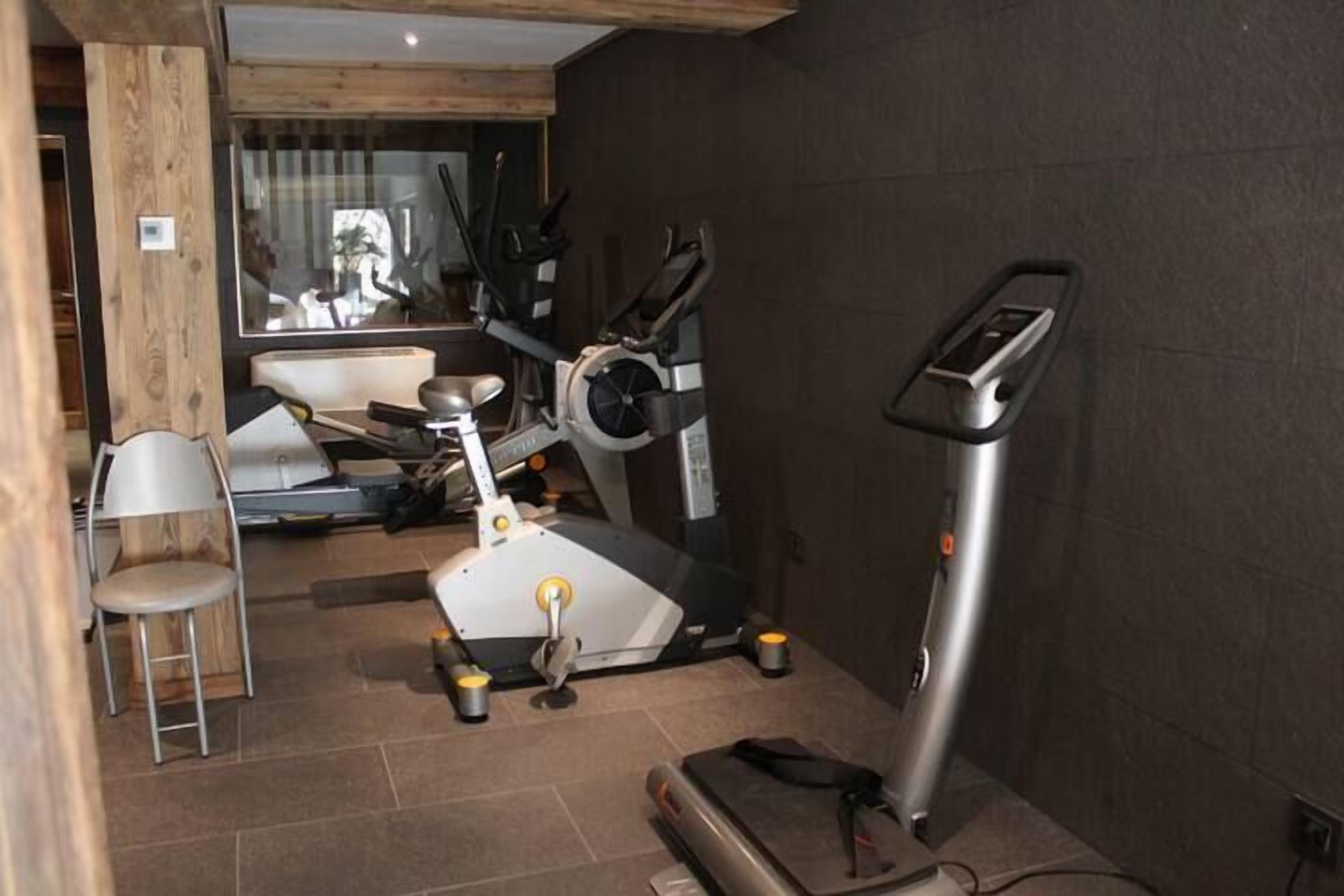 Una palestra in casa con attrezzature per allenamento, tra cui tapis roulant, cyclette e pesi.