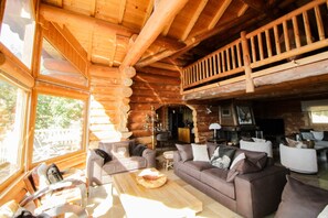 A log cabin interior with a living area, a dining table, and a kitchen.