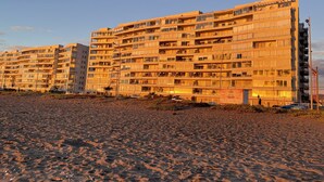 A multi-story building with numerous balconies and windows, situated next to a sandy area. - La Serena Vacations, Chile! (La Serena)