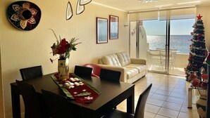 A dining area with a table set for four, a sofa, and a Christmas tree. - La Serena Vacations, Chile! (La Serena)