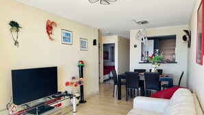 A modern living room with a flat-screen TV, a sofa, a dining area with a table and chairs, and a kitchen visible in the background. - La Serena Vacations, Chile! (La Serena)