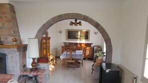 Un soggiorno accogliente con camino, un tavolo da pranzo con sedie, una televisione e un'ampia finestra.