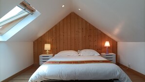 A bedroom with a sloped ceiling, wooden walls, a bed with white bedding, two bedside tables with lamps, and a skylight. - Between Quimper and Douarnenez, 10 minutes from the beach (Plogastel-Saint-Germain)