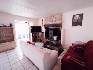 Ein Wohnzimmer mit Kamin, Fernseher, Bücherregal und einem roten Sofa.