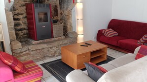 A cozy living room with a stone fireplace, a red sofa, a white sofa, and a wooden coffee table. - Between Quimper and Douarnenez, 10 minutes from the beach (Plogastel-Saint-Germain)