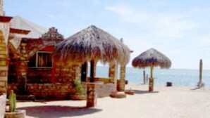 A beachside building with thatched-roof structures, a sandy beach, and the sea in the background. - Casa Baja, with panoramic view of the Sea of Cortez (San Felipe)