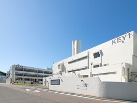 Un edificio moderno con letreros 'KEY1' y 'KEY2', que indican entradas separadas. Se ve un letrero que dice 'SEAMORE RESIDENCE', lo que sugiere un hotel o complejo residencial.