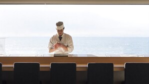 Una persona con uniforme detrás de un mostrador, con vista al mar.