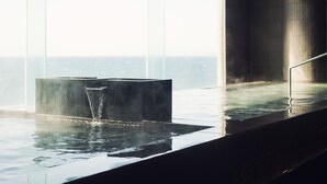 Piscina interior moderna con vistas despejadas al océano a través de amplios ventanales.
