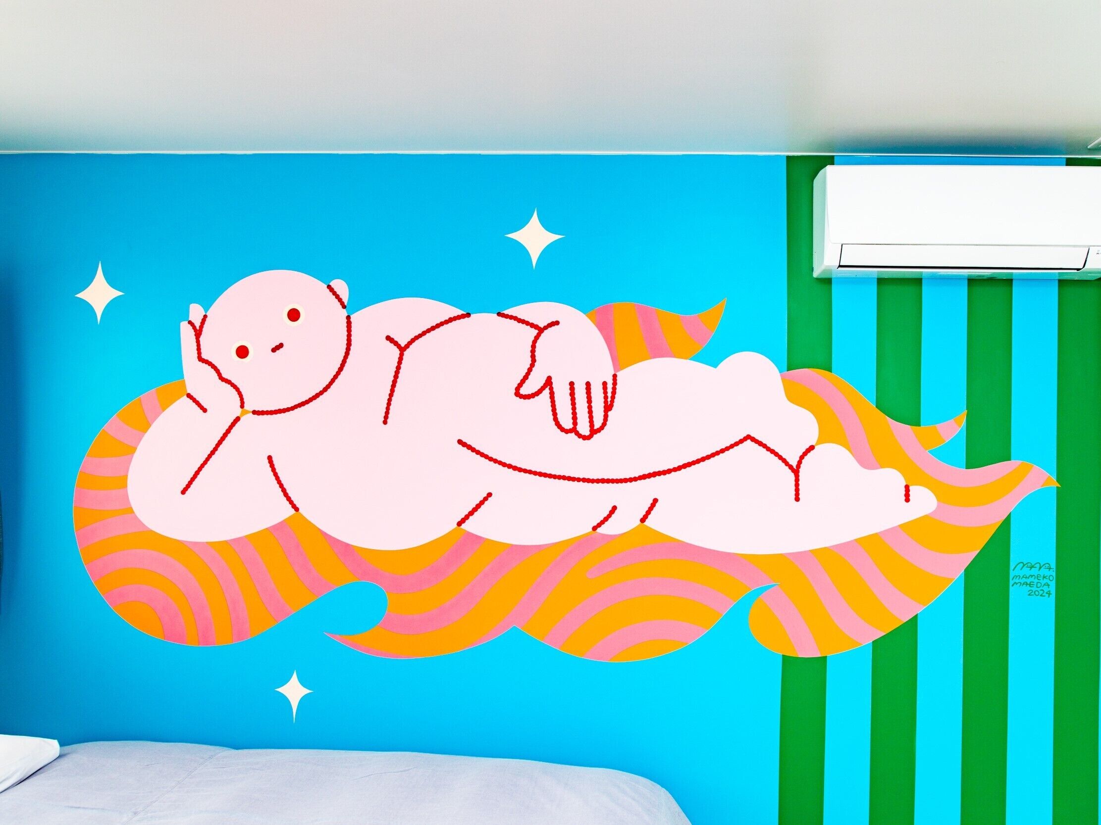 A room with a blue wall, a bed, and a wall-mounted air conditioner.