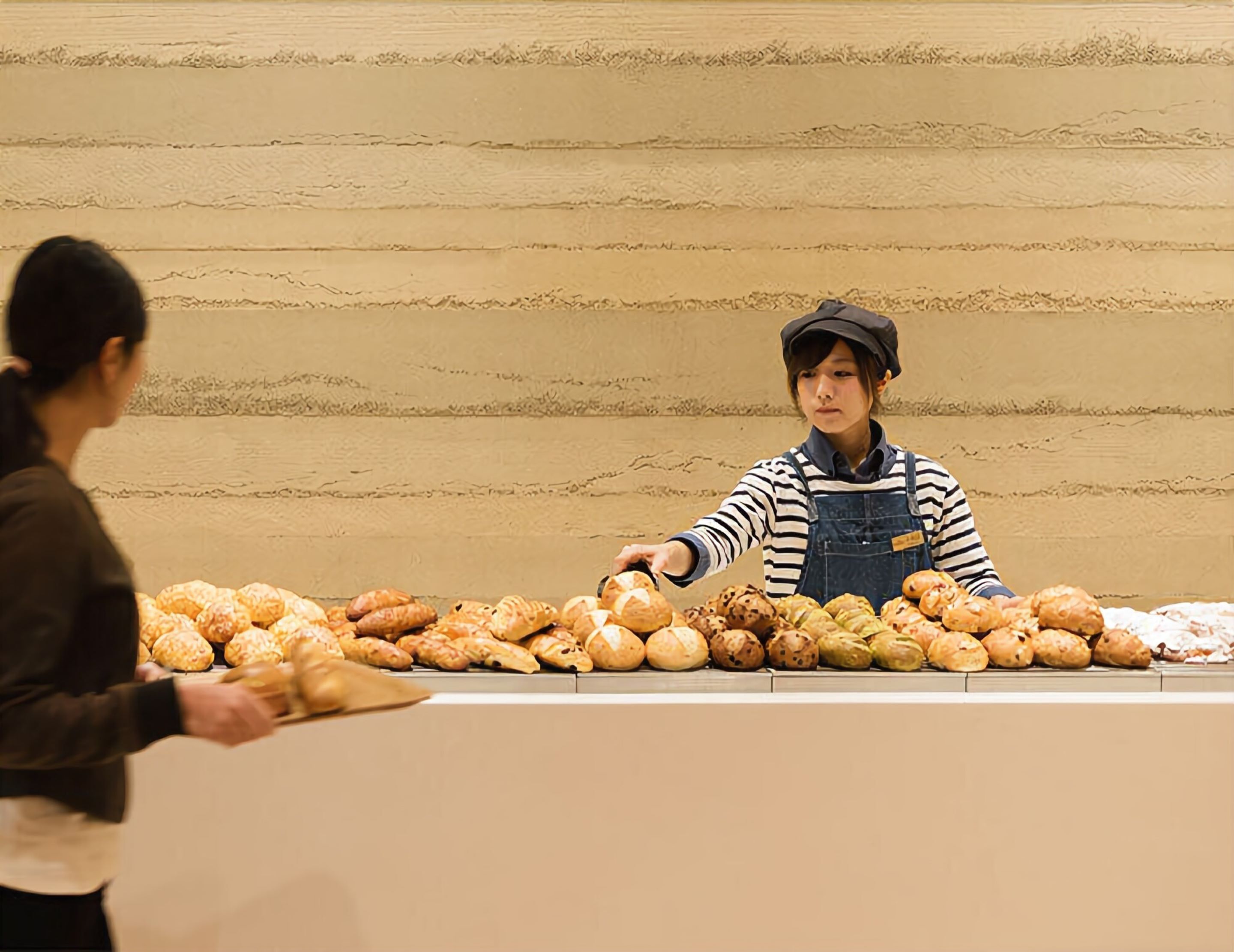 A bakery counter with various baked goods and a person serving.