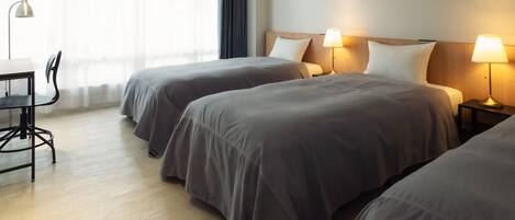 Habitación de hotel con dos camas, un escritorio y una silla.