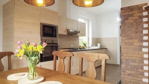 Eine moderne Küche mit Holzausbau, einem Esstisch mit Stühlen und einem Blumenstrauß auf dem Tisch.