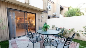 A patio with a round table and four chairs, a potted plant, and a sliding glass door leading to an interior space. - Spacious home in Anaheim 2bedrooms,2.5bathrooms -Ideal for corporate housing (Anaheim)