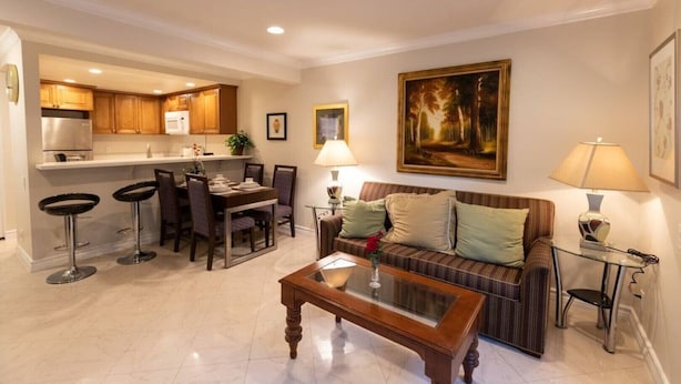 A modern living room with a glass coffee table, a sofa with cushions, a dining area with a table and chairs, and a kitchen in the background. - Spacious home in Anaheim 2bedrooms,2.5bathrooms -Ideal for corporate housing (Anaheim)