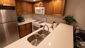 A kitchen with wooden cabinets, stainless steel appliances, a double sink, and potted plants. - Spacious home in Anaheim 2bedrooms,2.5bathrooms -Ideal for corporate housing (Anaheim)