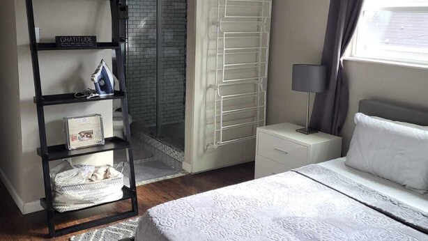 A bedroom with a bed, a nightstand, a lamp, a wardrobe, and a ladder. - Charming Heights Guesthouse! (Houston)