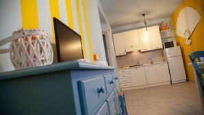 A kitchen with white cabinets, a microwave, and a sink. There is a blue chair and a yellow wall with a striped pattern.