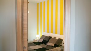 A bedroom with a bed, a nightstand, and a wall with vertical stripes.
