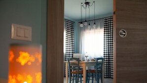 A dining area with a table and chairs, a chandelier, and checkered curtains.