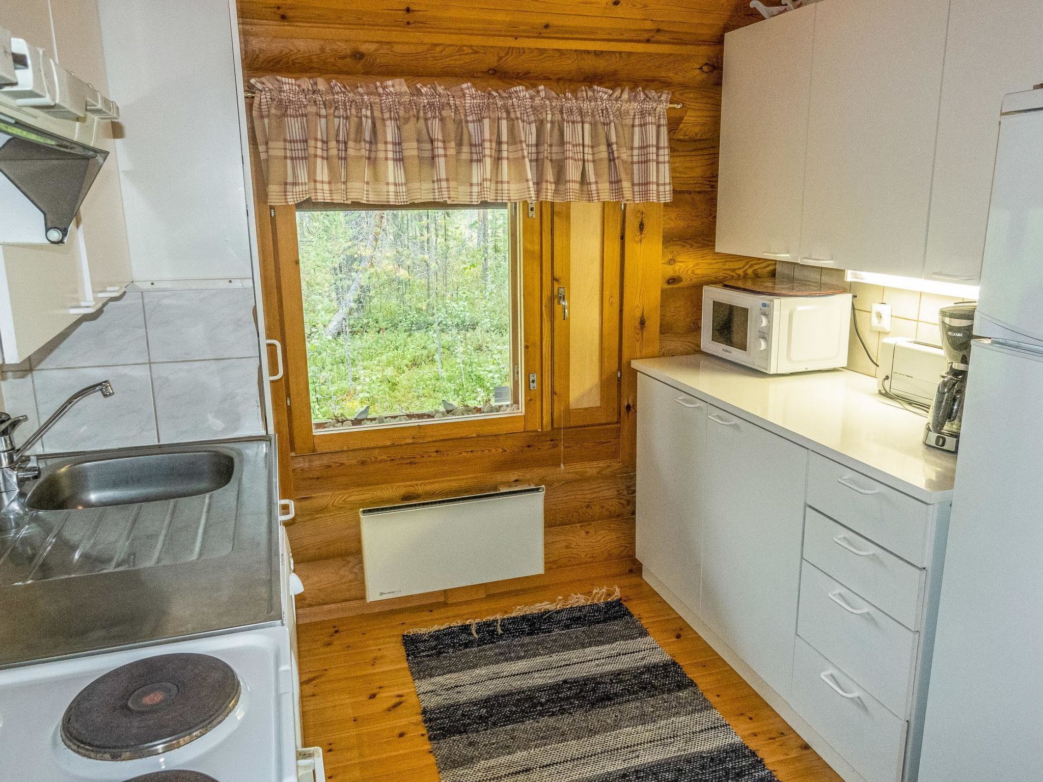 A compact kitchen with a window, a microwave, a toaster, and a sink.