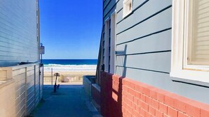 A narrow pathway leading to a beach, flanked by two buildings with a clear view of the ocean. - Find your beach bliss! (San Diego)