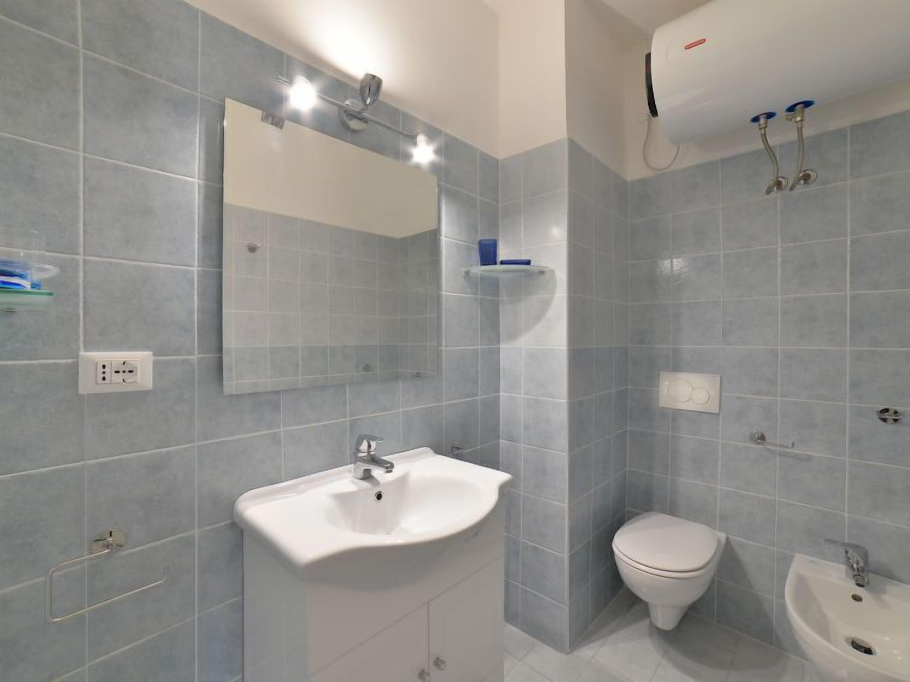 A modern bathroom with a white sink, a toilet, and a bidet.