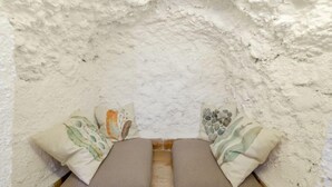Un coin accueillant avec deux bancs rembourrés adossés à un mur à texture, chacun agrémenté de coussins décoratifs.