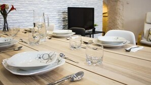 Une table à manger dressée avec des assiettes, des verres et des couverts, sur fond d’un mur blanc texturé et d’une enseigne indiquant le mot « GRANADA ».