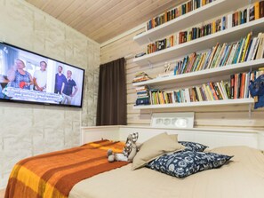 Un dormitori amb un llit, televisió i prestatges de llibres.