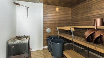 Un cuarto de sauna con sauna, bancos y cestos de basura.