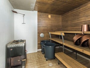 A sauna room with a sauna, benches, and trash bins.