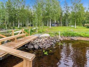 A wooden dock leading to a small house surrounded by a forest. - Suviranta by Interhome (Rautalampi)