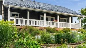 A two-story house with a covered porch and a garden in front.