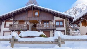 Un bâtiment de style chalet, avec une façade en bois, deux balcons et un toit recouvert de neige.