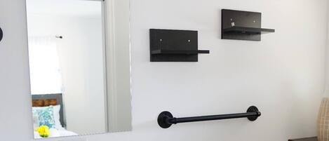 A modern bathroom with a white sink, black vanity, a mirror, a towel rack, and a toilet.