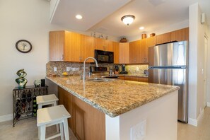 A kitchen with wooden cabinets, a stainless steel refrigerator, granite countertops, and a wine rack.