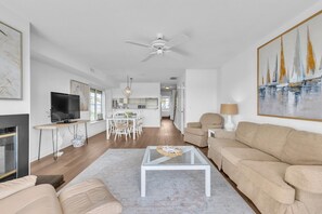 A modern living room with a TV, sofa, coffee table, and artwork.