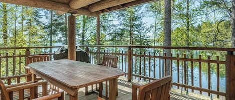 A wooden deck with a table and chairs overlooking a body of water.